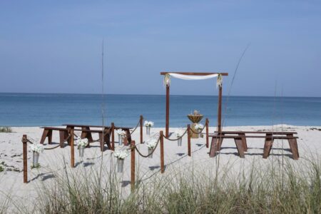 Handmade wooden boho beach wedding ceremony design with bench seating and roped aisle