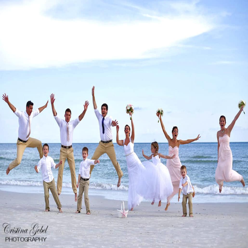 bridal party jumping by ocean beach wedding