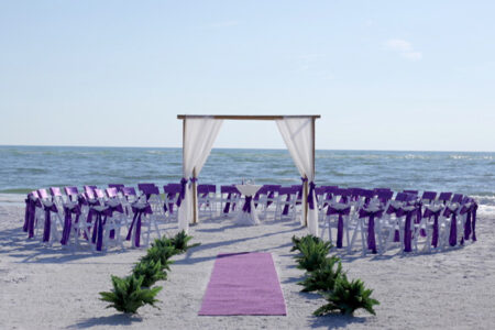 Purple and White Beach Wedding Ceremony Setup with Seats in a Circle Around the Couple