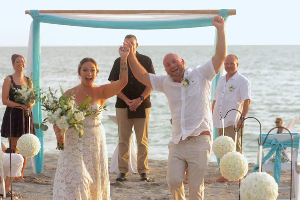 Happy bride and groom walk away from their Sarasota beach wedding ceremony